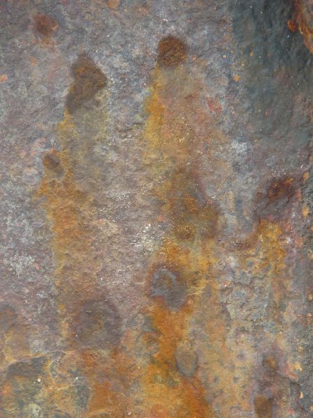 Rusted metal texture, formed into a rough, uneven surface in various hues of blue, yellow and red.